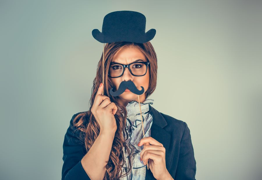 A woman with an obviously fake mustache and fake bowler hat