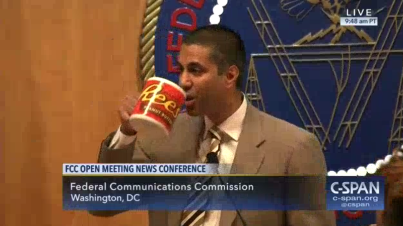 FCC Chairman Ajit Pai drinks from a large mug with the Reese's peanut butter cup logo