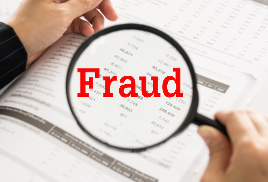 A magnifying glass overs over a spreadsheet, with the word "Fraud" superimposed in red text