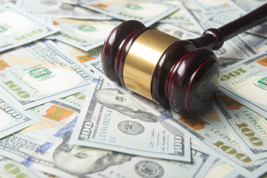 a gavel sits on a pile of hundred dollar bills