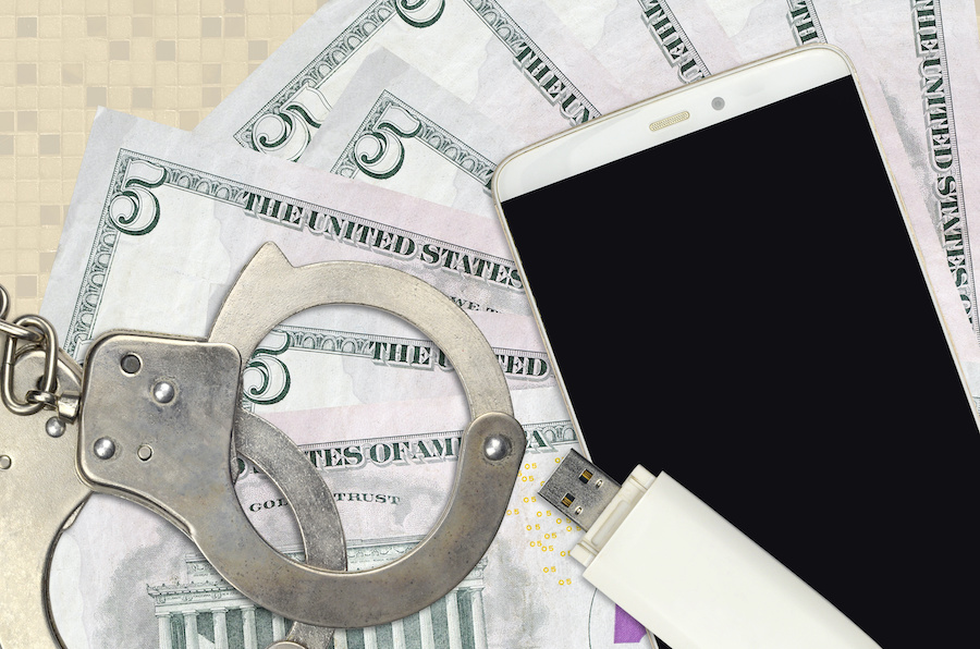 still life with handcuffs, smartphone, flash drive, and five dollar bills (american)