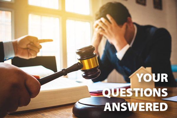 A man holds his head in his hands while a judge points at him and bangs a gavel