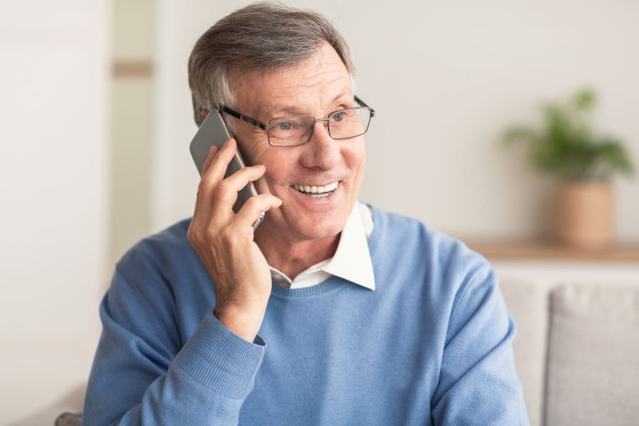 Elderly Man Talking On Cellphone Sitting On Couch At Home