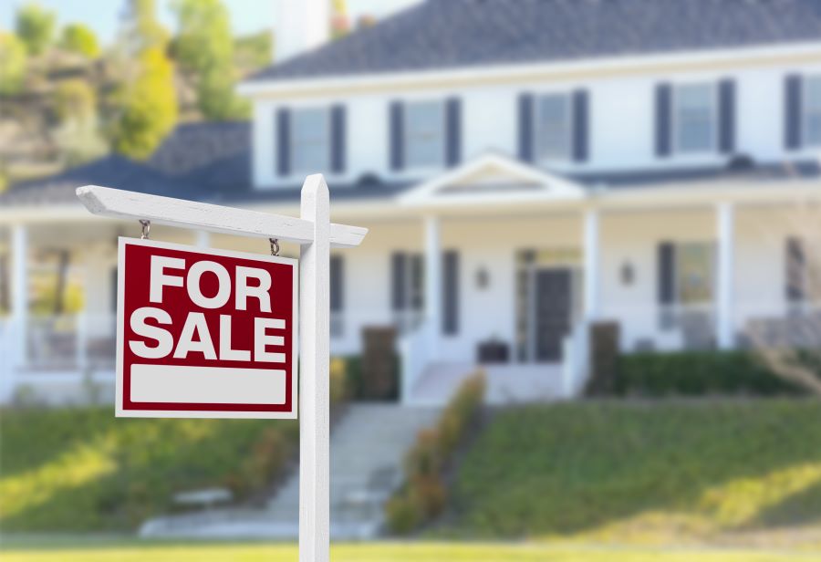 A large home with a "FOR SALE" sign