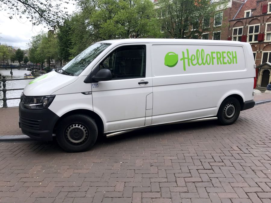 A HelloFresh van is parked on a bridge over a river in a city.