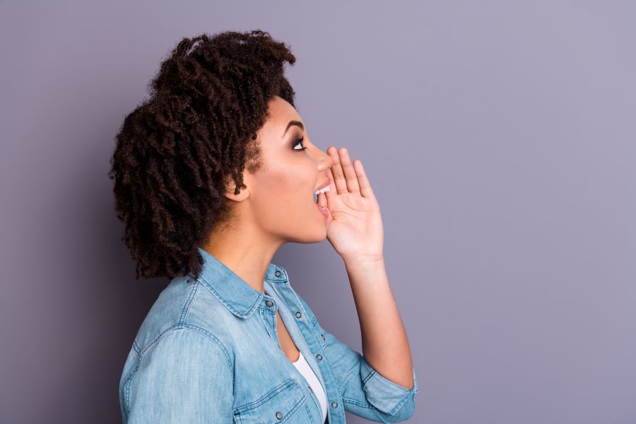 A woman is yelling with her cupped hand for additional volume (or possibly just for show)