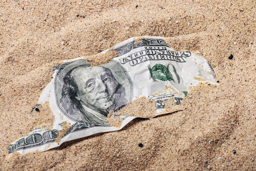 100 dollar bill buried in the sand