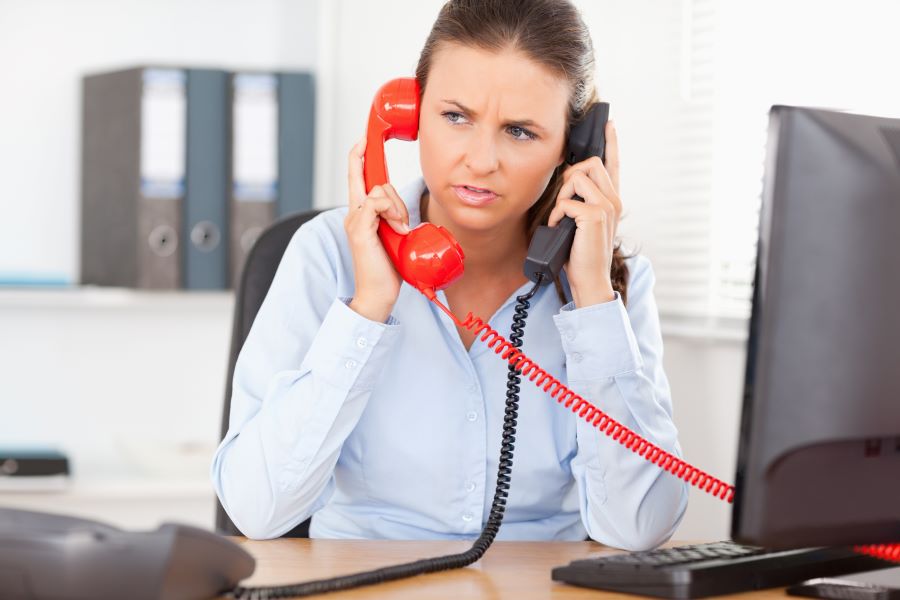 A businesswoman is talking on two phones—one black, one red—at the same time